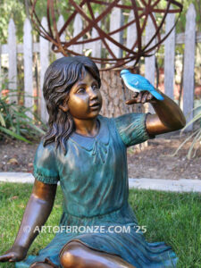 Wings of Joy bronze sculpture of sitting girl in dress with bronze bird perched on her hand