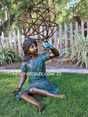 Wings of Joy bronze sculpture of sitting girl in dress with bronze bird perched on her hand
